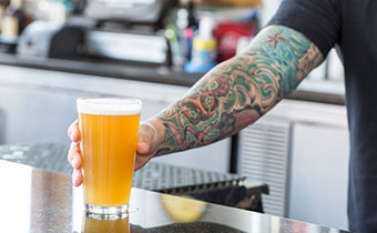 bartender placing beer pint on bar top