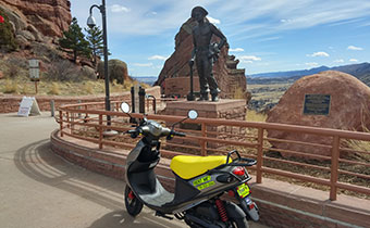 scooter in front of red rocks miner statue